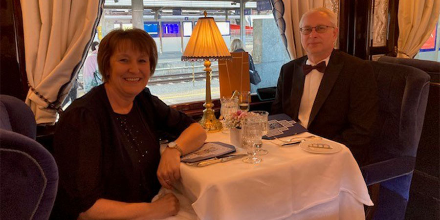 Couple seated and smiling, in one of the restaurants aboard the Venice Simplon Orient Express. 